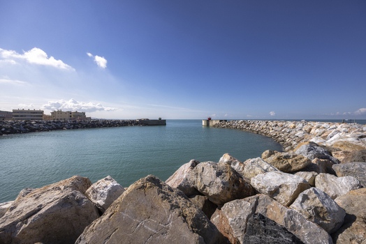 View of the stone breakwaters protecting the harbor entrance under a clear blue sky in Marina di Pisa Tuscany Italy.