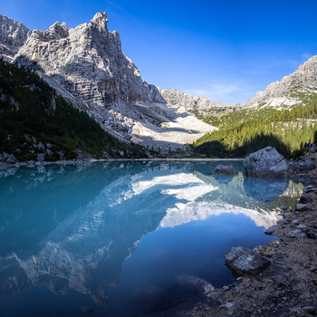 View of the turquoise waters of Lake Sorapis reflecting the surrounding jagged Dolomite peaks and pine forests in Cortina d Ampezzo Veneto Italy.