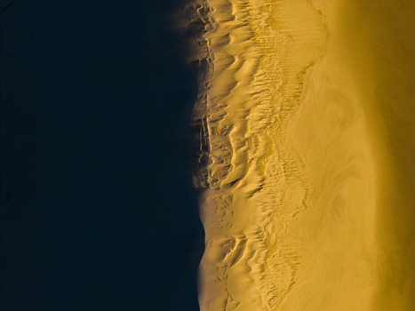 Aerial view of golden sand dunes with intricate wind swept ripples and textures meeting deep shadows at Two Peoples Bay Nature Reserve in Albany Western Australia Australia.