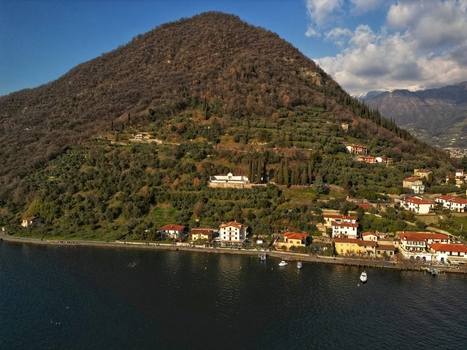 Aerial view of Monte Isola island with houses along the shore and olive groves on the hillside overlooking Lake Iseo Monte Isola Lombardy Italy. Aerial view of Monte Isola island with houses along the shore and olive groves on the hillside overlooking Lake Iseo Monte Isola Lombardy Italy.