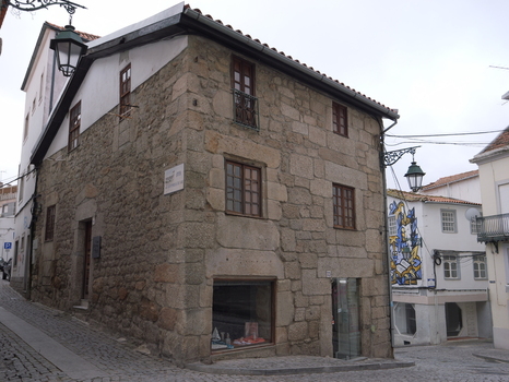 View of a historic stone building with traditional architecture and a shop window on a cobblestone street in Covilha Castelo Branco District Portugal.