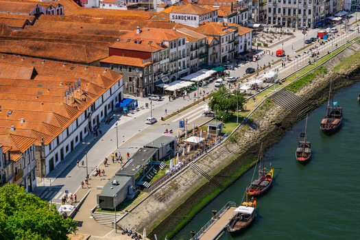 Aerial view of the Douro River embankment with its tiled roofs and historic buildings reflecting warm sunlight contrasted by the cool river Porto Porto District Portugal. Aerial view of the Douro River embankment with its tiled roofs and historic buildings reflecting warm sunlight contrasted by the cool river Porto Porto District Portugal.