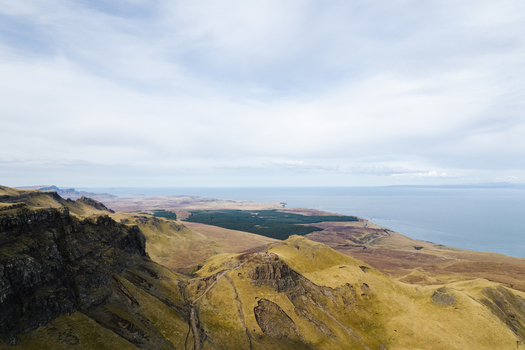 Aerial view of The Storr with rugged cliffs and grassy slopes overlooking the sea in Portree Scotland United Kingdom. Aerial view of The Storr with rugged cliffs and grassy slopes overlooking the sea in Portree Scotland United Kingdom.