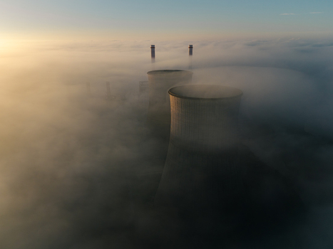 Aerial view of the RWE Clauscentrale power plant cooling towers and chimneys emerging from a thick layer of morning fog at sunrise in Maasbracht Limburg Netherlands. Aerial view of the RWE Clauscentrale power plant cooling towers and chimneys emerging from a thick layer of morning fog at sunrise in Maasbracht Limburg Netherlands.