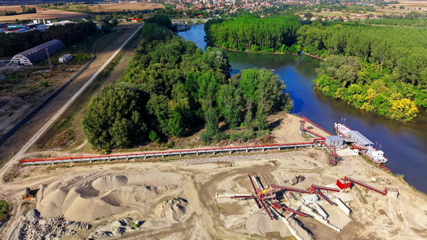 Aerial view of a gravel and sand extraction site with a long conveyor belt and a barge docked on the riverbank near Kovin Vojvodina Serbia. Aerial view of a gravel and sand extraction site with a long conveyor belt and a barge docked on the riverbank near Kovin Vojvodina Serbia.