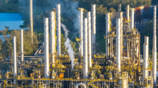 Aerial view of a large petrochemical complex with tall industrial chimneys emitting smoke intricate piping systems and surrounding greenery in Santo Andre State of Sao Paulo Brazil.