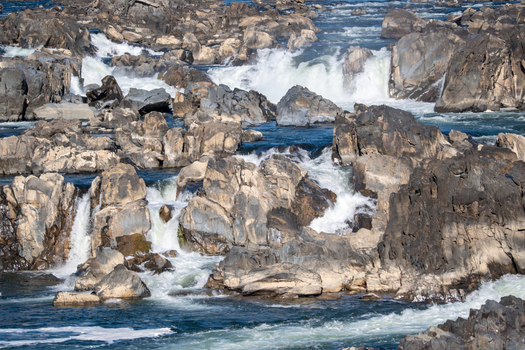 View of the rushing waters cascading over the rugged grey rocks creating a dynamic display of power and beauty in nature Great Falls Virginia United States. View of the rushing waters cascading over the rugged grey rocks creating a dynamic display of power and beauty in nature Great Falls Virginia United States.