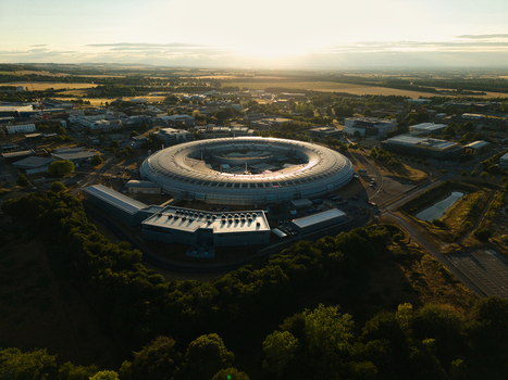Aerial view of Diamond Light Source a circular synchrotron facility surrounded by greenery under golden hour light in Didcot United Kingdom.