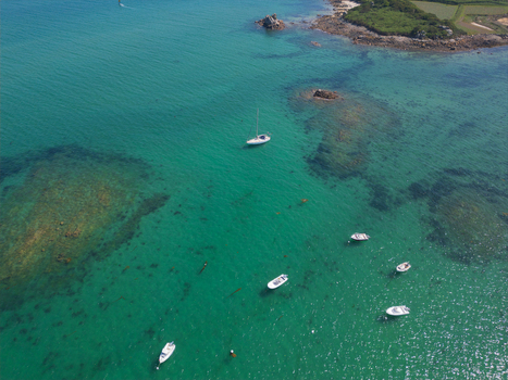 Aerial view of the turquoise waters of Plage de Port Blanc with small white boats anchored near the rocky coastline in Penvenan Bretagne France. Aerial view of the turquoise waters of Plage de Port Blanc with small white boats anchored near the rocky coastline in Penvenan Bretagne France.