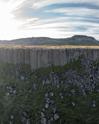 Aerial view of Gerduberg Cliffs featuring basalt columns mossy slopes and rocky terrain under a bright sky in Raudhamelur Eyja og Miklaholtshr Iceland. Aerial view of Gerduberg Cliffs featuring basalt columns mossy slopes and rocky terrain under a bright sky in Raudhamelur Eyja og Miklaholtshr Iceland.