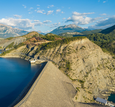 Aerial view of Serre Poncon Dam and mountain reservoir surrounded by rugged alpine landscape in Rousset Serre Poncon Provence Alpes Cote d Azur France.
