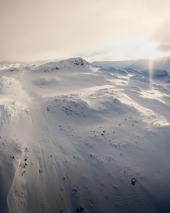 Aerial view of the snow covered Gaustablikk mountain landscape featuring vast white slopes rocky outcrops and soft golden hour sunlight in Rjukan Telemark Norway. Aerial view of the snow covered Gaustablikk mountain landscape featuring vast white slopes rocky outcrops and soft golden hour sunlight in Rjukan Telemark Norway.