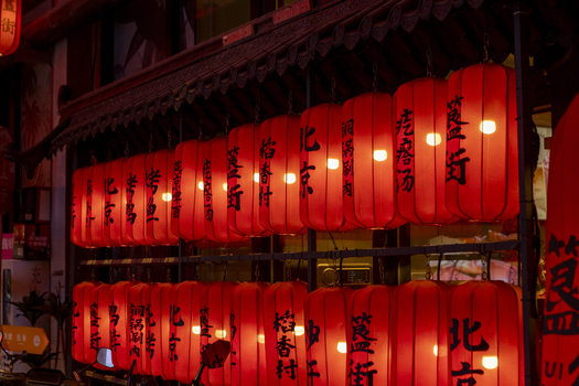 View of traditional red lanterns with Chinese calligraphy hanging under a wooden roof at night in Beijing Beijing China. View of traditional red lanterns with Chinese calligraphy hanging under a wooden roof at night in Beijing Beijing China.