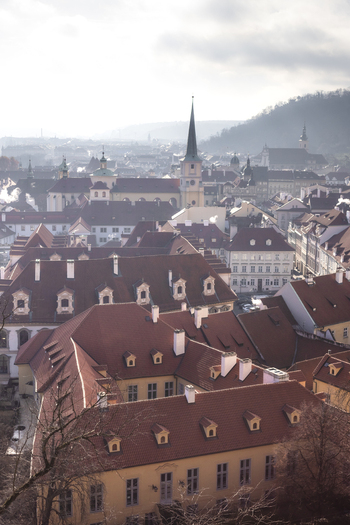 View of historic red tiled rooftops and church spires under a hazy sky in the Mala Strana district Prague Prague Czechia. View of historic red tiled rooftops and church spires under a hazy sky in the Mala Strana district Prague Prague Czechia.