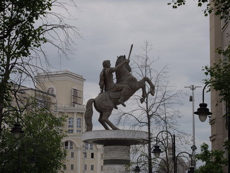 View of the Alexander the Great Statue on its pedestal surrounded by neoclassical buildings and trees under a cloudy sky in Skopje Greater Skopje North Macedonia.