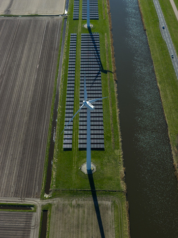 Aerial view of a wind turbine and rows of solar panels situated between a canal and cultivated fields under bright sunlight Netherlands. Aerial view of a wind turbine and rows of solar panels situated between a canal and cultivated fields under bright sunlight Netherlands.