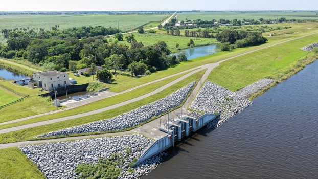 Aerial view of the water control structure and lock system at Pahokee surrounded by green agricultural fields and canal embankments in Pahokee Florida United States.