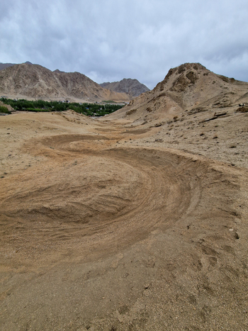 View of a winding dirt track through the arid mountainous landscape of Leh Ladakh India.