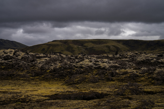 View of moss covered lava fields stretch under a heavy brooding sky the muted greens and greys painting a stark otherworldly landscape Skaftárhreppur Iceland. View of moss covered lava fields stretch under a heavy brooding sky the muted greens and greys painting a stark otherworldly landscape Skaftárhreppur Iceland.