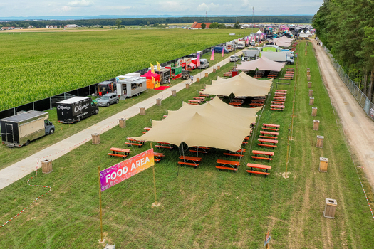 Herzogenaurach Germany 25 July 2025 Aerial view of the food area at Open Beatz Festival featuring large tents food trucks and picnic tables arranged on a grassy field near a forest. Herzogenaurach Germany 25 July 2025 Aerial view of the food area at Open Beatz Festival featuring large tents food trucks and picnic tables arranged on a grassy field near a forest.