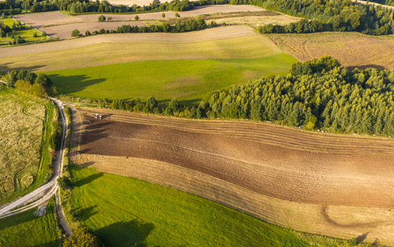 Aerial view of a tractor plowing a field in the Kashubia region Pomeranian Voivodeship Poland. Aerial view of a tractor plowing a field in the Kashubia region Pomeranian Voivodeship Poland.