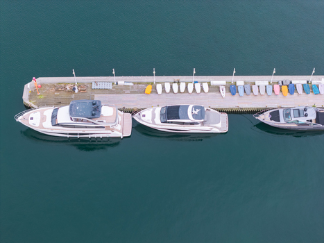 Aerial view of luxury yachts moored at a wooden pier with small sailboats lined up along the dock in the Baltic Sea in Sopot Pomeranian Voivodeship Poland. Aerial view of luxury yachts moored at a wooden pier with small sailboats lined up along the dock in the Baltic Sea in Sopot Pomeranian Voivodeship Poland.