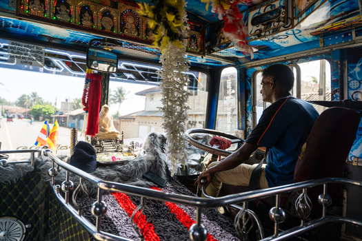 Sri Lanka 31 January 2026 View of the interior of a colorful bus with a driver sitting at the wheel and a dashboard decorated with religious icons and garlands.