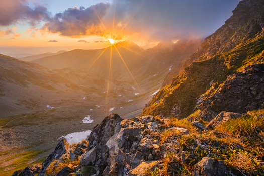 View of Smutne sedlo in Western Tatras during a golden sunset with a sunburst over rugged mountain peaks and rocky slopes Ziar Zilina Region Slovakia. View of Smutne sedlo in Western Tatras during a golden sunset with a sunburst over rugged mountain peaks and rocky slopes Ziar Zilina Region Slovakia.