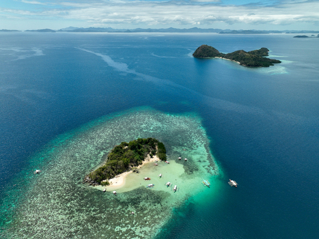 Aerial view of CYC Beach in Coron featuring turquoise waters coral reefs and traditional outrigger boats anchored near the sandy shore Coron Mimaropa Philippines. Aerial view of CYC Beach in Coron featuring turquoise waters coral reefs and traditional outrigger boats anchored near the sandy shore Coron Mimaropa Philippines.