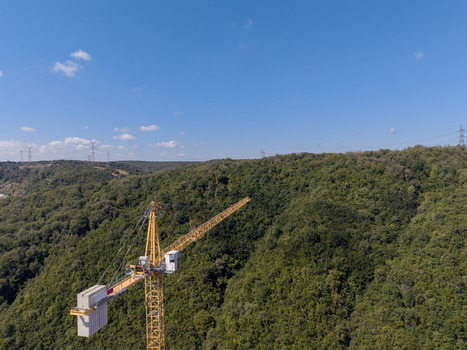 Aerial view of a yellow construction crane standing amidst a dense green forest under a clear blue sky in Istanbul Istanbul Turkiye. Aerial view of a yellow construction crane standing amidst a dense green forest under a clear blue sky in Istanbul Istanbul Turkiye.