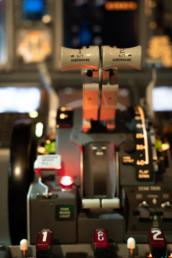 View of the throttle quadrant and flight controls inside a Boeing 737 800 cockpit with illuminated buttons and levers in Langenhagen Niedersachsen Germany. View of the throttle quadrant and flight controls inside a Boeing 737 800 cockpit with illuminated buttons and levers in Langenhagen Niedersachsen Germany.