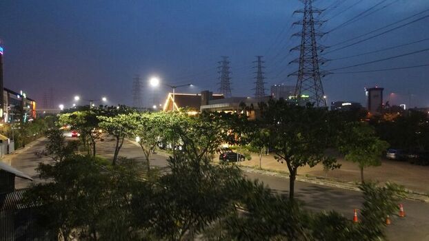 Aerial view of Grand Kota Bintang illuminated at night with surrounding trees parking area and power lines in Kecamatan Bekasi Barat Jawa Barat Indonesia. Aerial view of Grand Kota Bintang illuminated at night with surrounding trees parking area and power lines in Kecamatan Bekasi Barat Jawa Barat Indonesia.