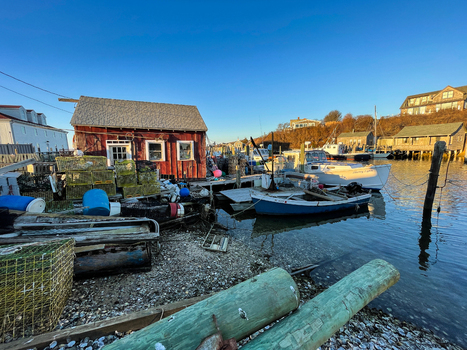 View of Martha s Vineyard harbor with a red fishing shack lobster traps and boats docked in the calm water under a clear sky in Edgartown Massachusetts United States.
