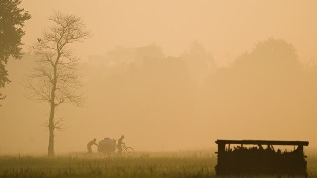 View of people in a foggy field in Bangladesh.