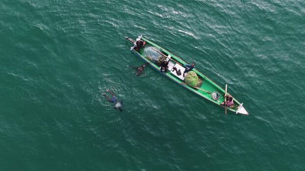 Aerial view of fishermen on a green boat in turquoise waters India. Aerial view of fishermen on a green boat in turquoise waters India.