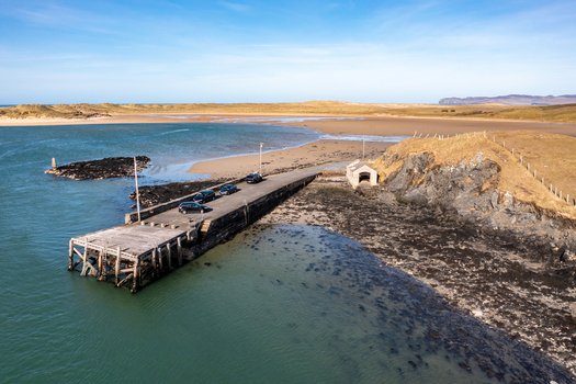 Aerial view of Ballyness Bay pier with parked cars on the concrete jetty rocky coastline and sandy beach in Ballyness County Donegal Ireland. Aerial view of Ballyness Bay pier with parked cars on the concrete jetty rocky coastline and sandy beach in Ballyness County Donegal Ireland.