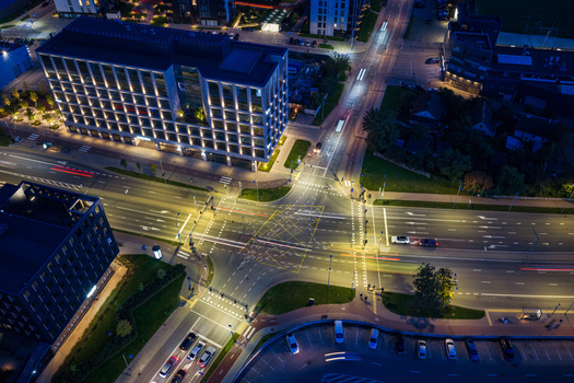 Aerial view of a modern urban intersection at night with illuminated office buildings and light trails from moving cars in Vilnius Vilnius County Lithuania. Aerial view of a modern urban intersection at night with illuminated office buildings and light trails from moving cars in Vilnius Vilnius County Lithuania.