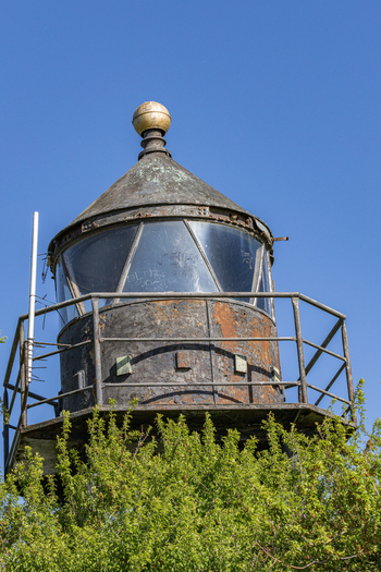 View of the weathered top of the Dangast lighthouse with its glass lantern room and golden sphere against a clear blue sky in Varel Lower Saxony Germany. View of the weathered top of the Dangast lighthouse with its glass lantern room and golden sphere against a clear blue sky in Varel Lower Saxony Germany.