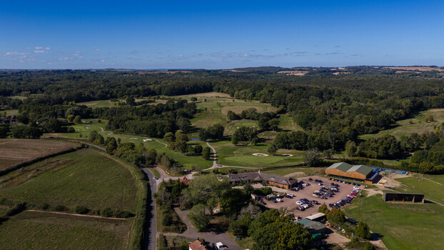 Aerial view of Hamptworth Golf course with lush green fairways sand bunkers surrounding woodland and the clubhouse with a parking lot in Hamptworth England United Kingdom. Aerial view of Hamptworth Golf course with lush green fairways sand bunkers surrounding woodland and the clubhouse with a parking lot in Hamptworth England United Kingdom.