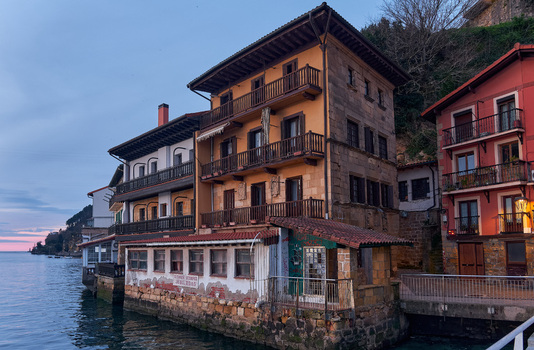 Pasai Donibane Spain 09 March 2026 View of traditional waterfront houses with wooden balconies along the harbor street at dusk.