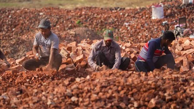 View of men breaking red bricks with hammers in Bogura Bangladesh.
