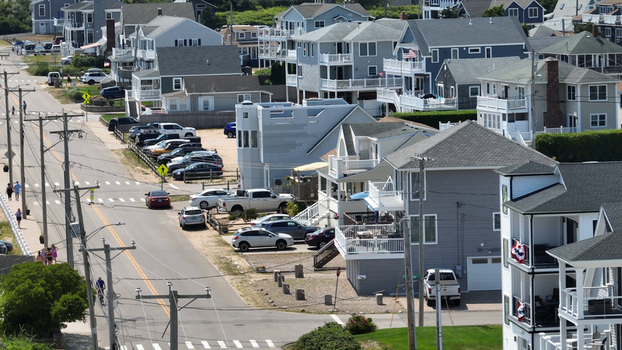 Aerial view of Misquamicut Beach area featuring coastal residential houses a street with parked cars and pedestrians in Westerly Rhode Island United States. Aerial view of Misquamicut Beach area featuring coastal residential houses a street with parked cars and pedestrians in Westerly Rhode Island United States.