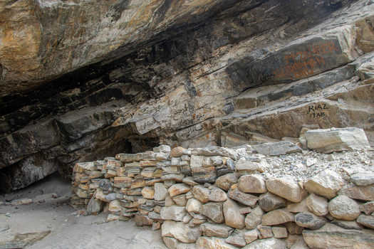 View of a rock shelter with a dry stone wall and inscriptions on the rock face at K2 Base Camp in Ghakhar Gilgit Pakistan. View of a rock shelter with a dry stone wall and inscriptions on the rock face at K2 Base Camp in Ghakhar Gilgit Pakistan.