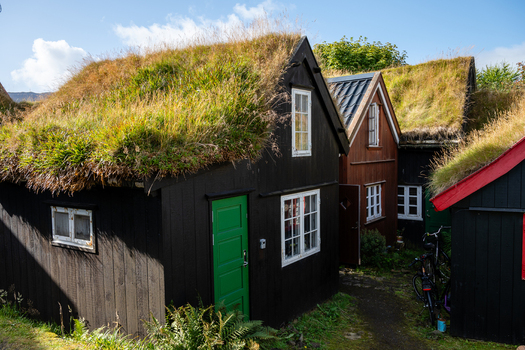 View of traditional turf roofed houses with black wooden walls and green grass roofs in the Faroe Islands. View of traditional turf roofed houses with black wooden walls and green grass roofs in the Faroe Islands.