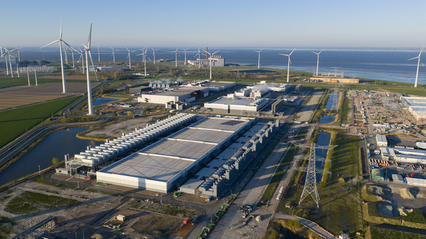 Aerial view of a large industrial data center complex and wind farm under a clear blue sky near the coast in Eemshaven Groningen Netherlands. Aerial view of a large industrial data center complex and wind farm under a clear blue sky near the coast in Eemshaven Groningen Netherlands.