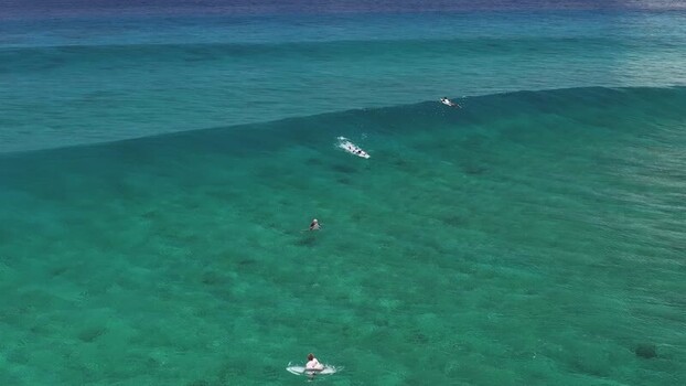 Aerial view of surfers on turquoise waves in Thulusdhoo Maldives.