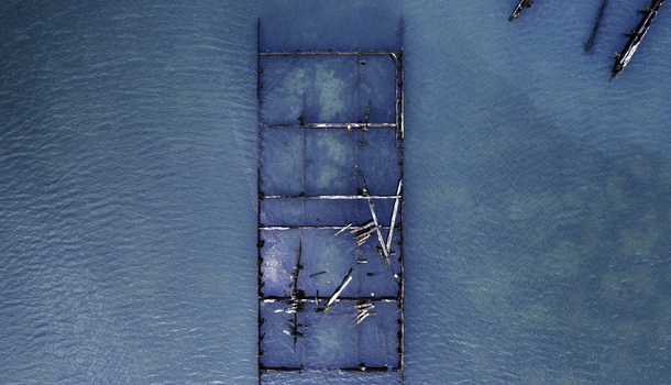Aerial view of the submerged wooden remains of a pier structure in the clear blue waters off the coast of Coney Island Kings County New York United States. Aerial view of the submerged wooden remains of a pier structure in the clear blue waters off the coast of Coney Island Kings County New York United States.