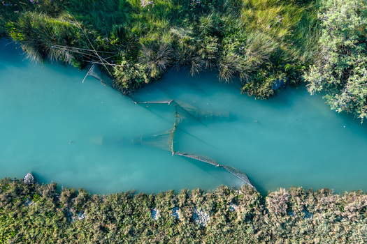 Aerial view of the turquoise water of Kanali i Vivarit with traditional fishing nets and lush green vegetation on the banks in Vrine Vlore County Albania. Aerial view of the turquoise water of Kanali i Vivarit with traditional fishing nets and lush green vegetation on the banks in Vrine Vlore County Albania.