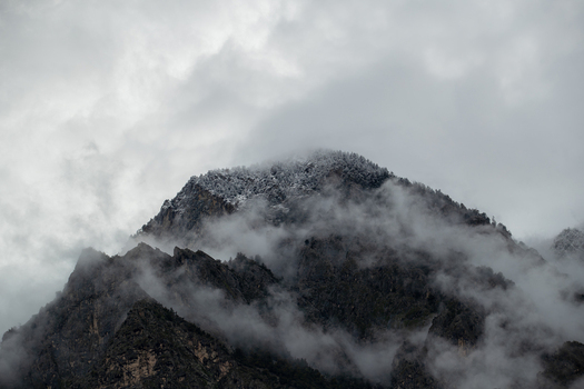 View of snow capped mountain peak shrouded in thick clouds and mist under a grey sky near Chilas Gilgit Pakistan. View of snow capped mountain peak shrouded in thick clouds and mist under a grey sky near Chilas Gilgit Pakistan.