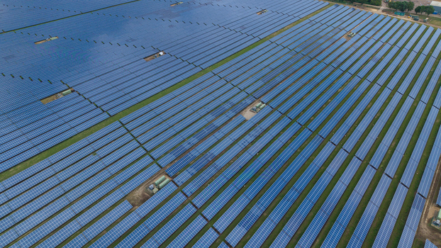 Aerial view of a large array of photovoltaic solar panels arranged in neat rows across a green field in Chittering England United Kingdom.